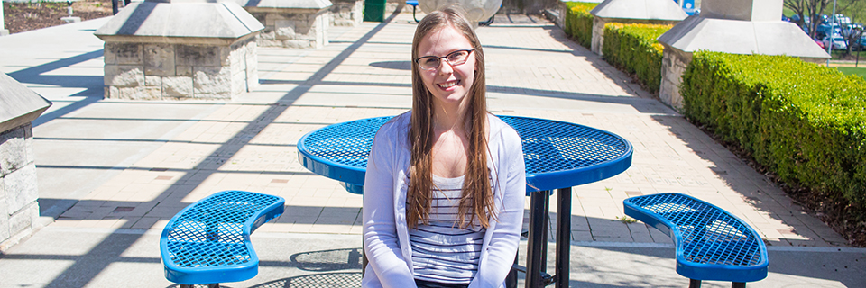 Alexandra Meyer sits at a table under the pergola