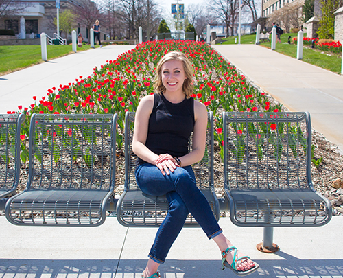 Annika Svoboda sits in front of some tulips on campus