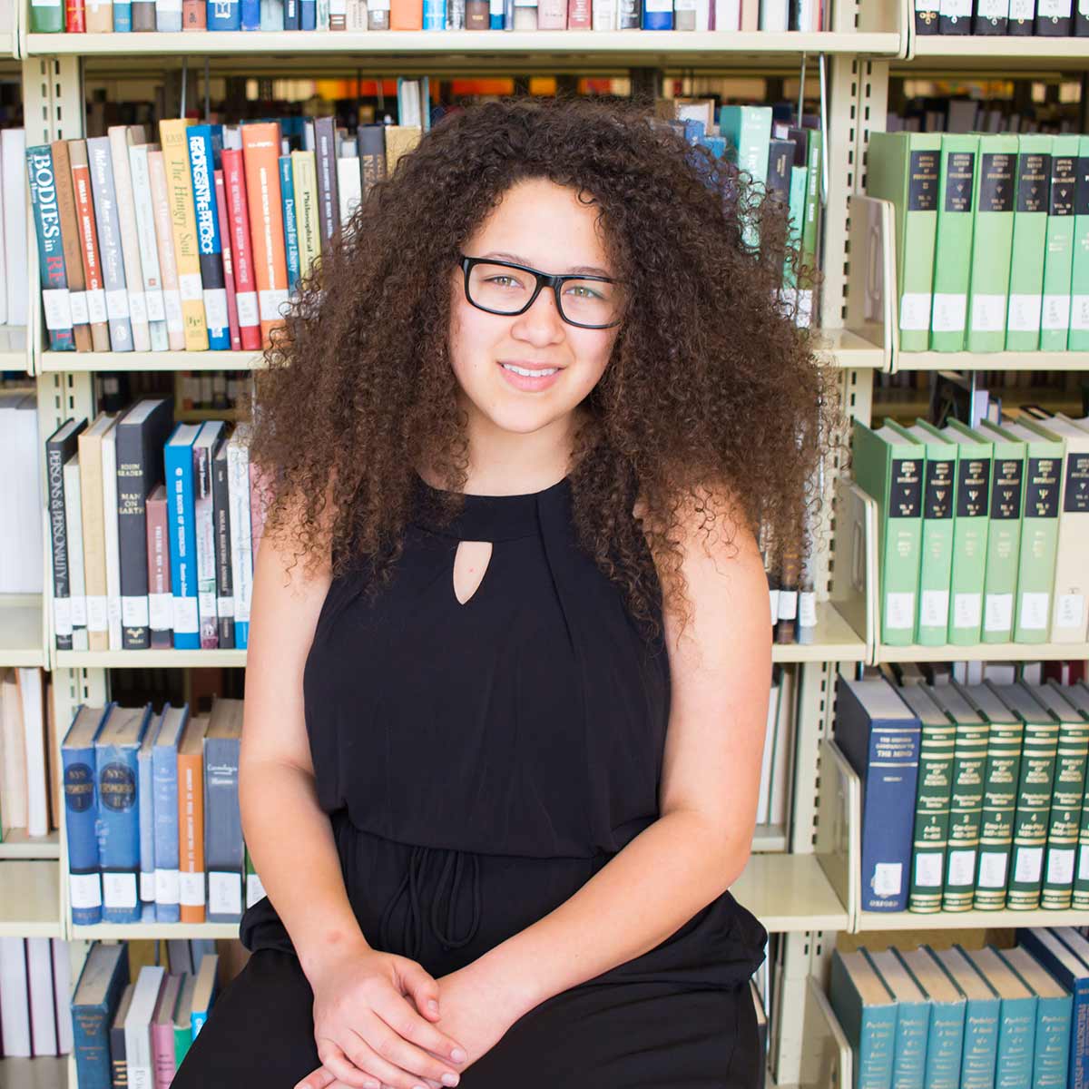 Veronica Clay sits in front of books in the library.