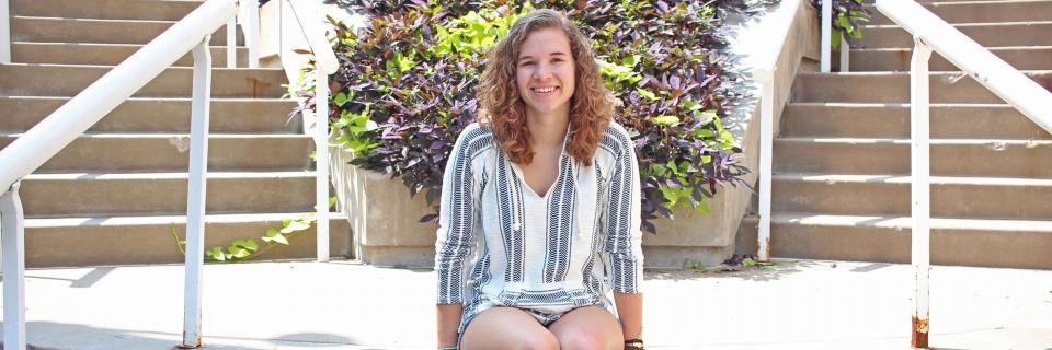 Emma Busch sits on steps on campus. 