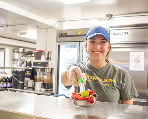 Laura Pezold serves fruit at NourishKC.