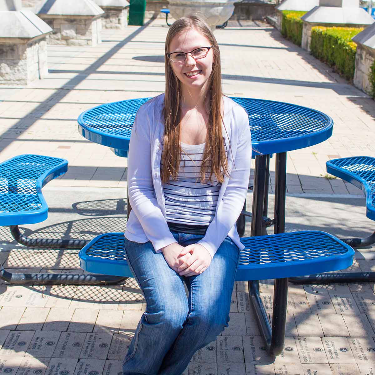 Alexandra Meyer sits at a table under the pergola. 