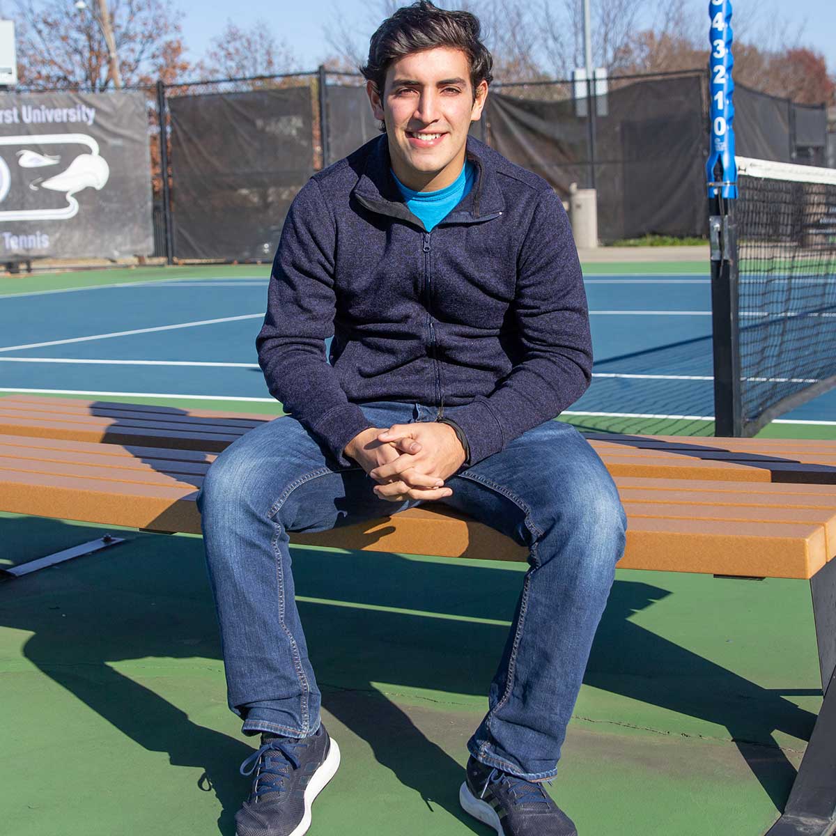 Nico Leon sits on a bench on the tennis courts.