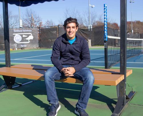 Nico Leon sits on a bench on the tennis courts. 