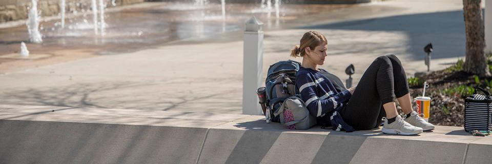 Student reads near bell tower on campus.