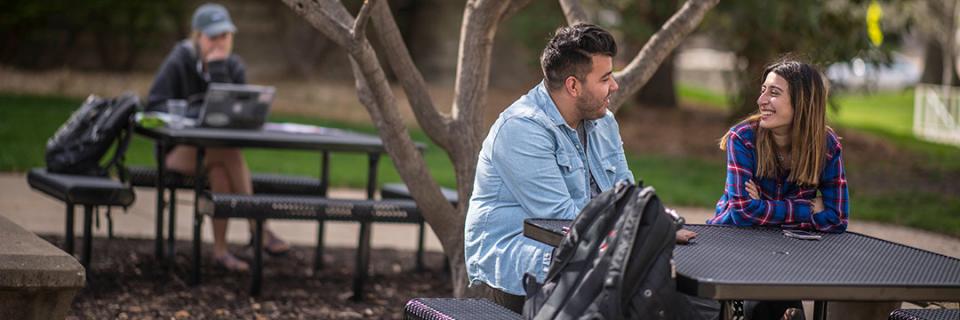 Students sit together at picnic table. 