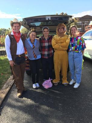 Students in Halloween costume at their service learning site Students in Halloween costume await trunk-or-treaters