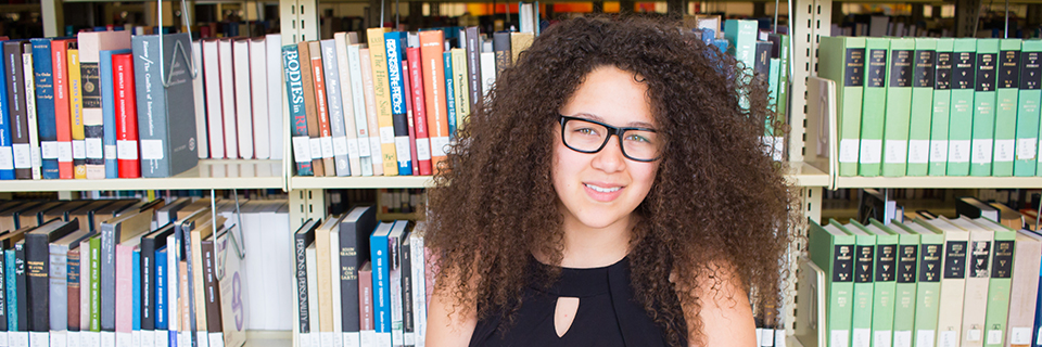 Veronica Clay sits in front of books in the library