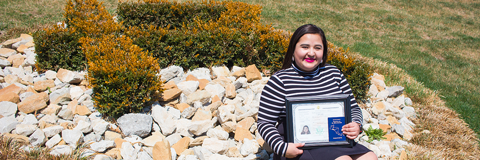 Virginia Vanegas, '18 Virginia Vanegas sits in front of the Rockhurst "R" shrub