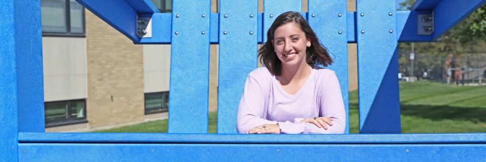 Caroline Adams sits in the big blue Adirondack chair on campus.