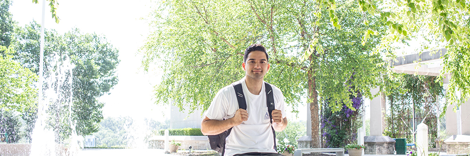 Cesar Aldana sits near the fountains on Rockhurst's campus