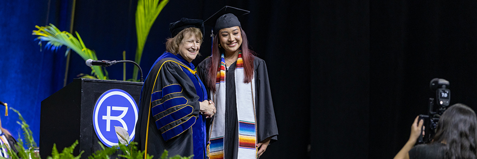 Dr. Cassady shaking hands with graduate getting photographed on stage at 2023 Commencement
