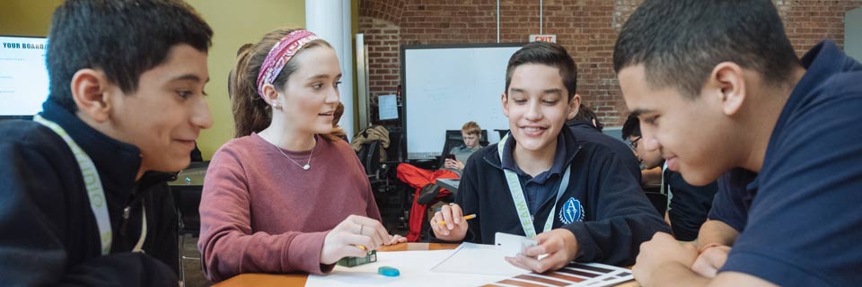 An educational studies student works with high schoolers on a project