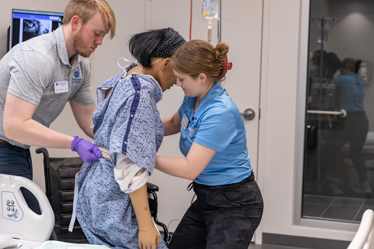 PT students help get a mannequin out of bed