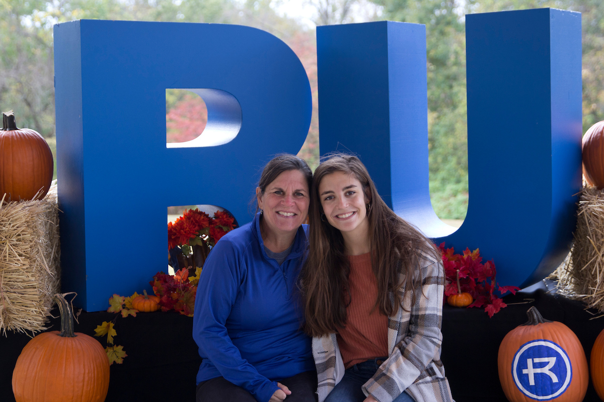 A mother and daughter pose for the camera at a fall photo background setting.