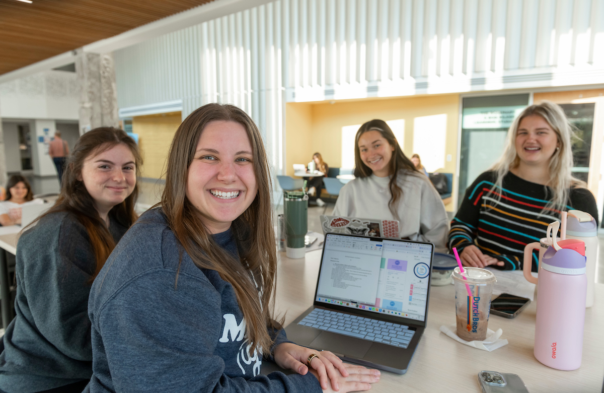 group of four female students smiling at the camera