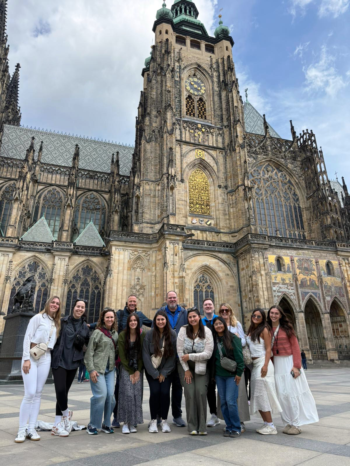 The group stands in front of a church in Prague, Czechia