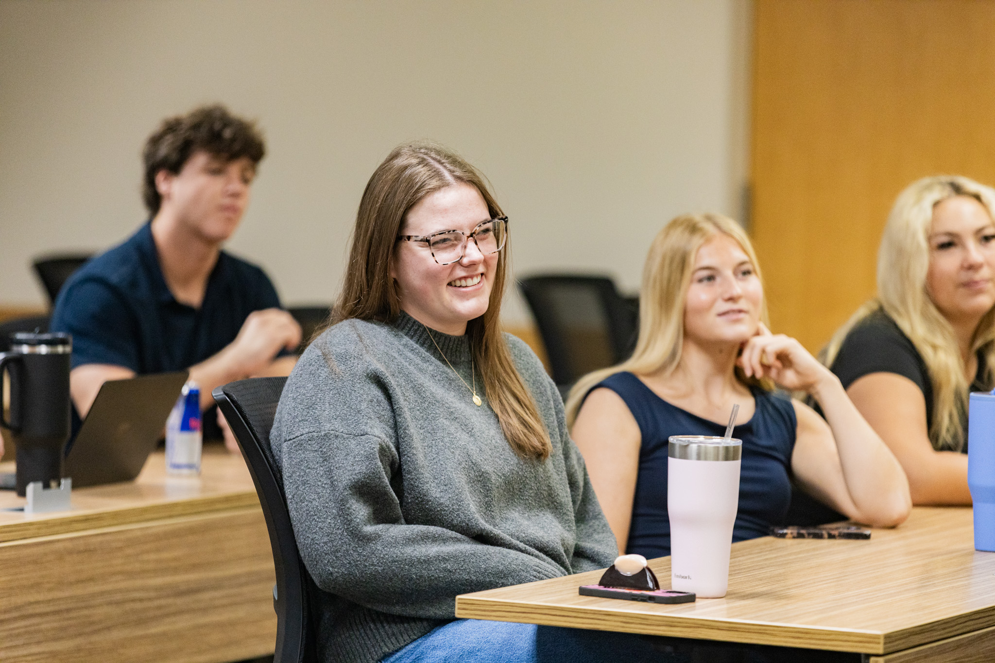 Three women and a man sit in class, smiling