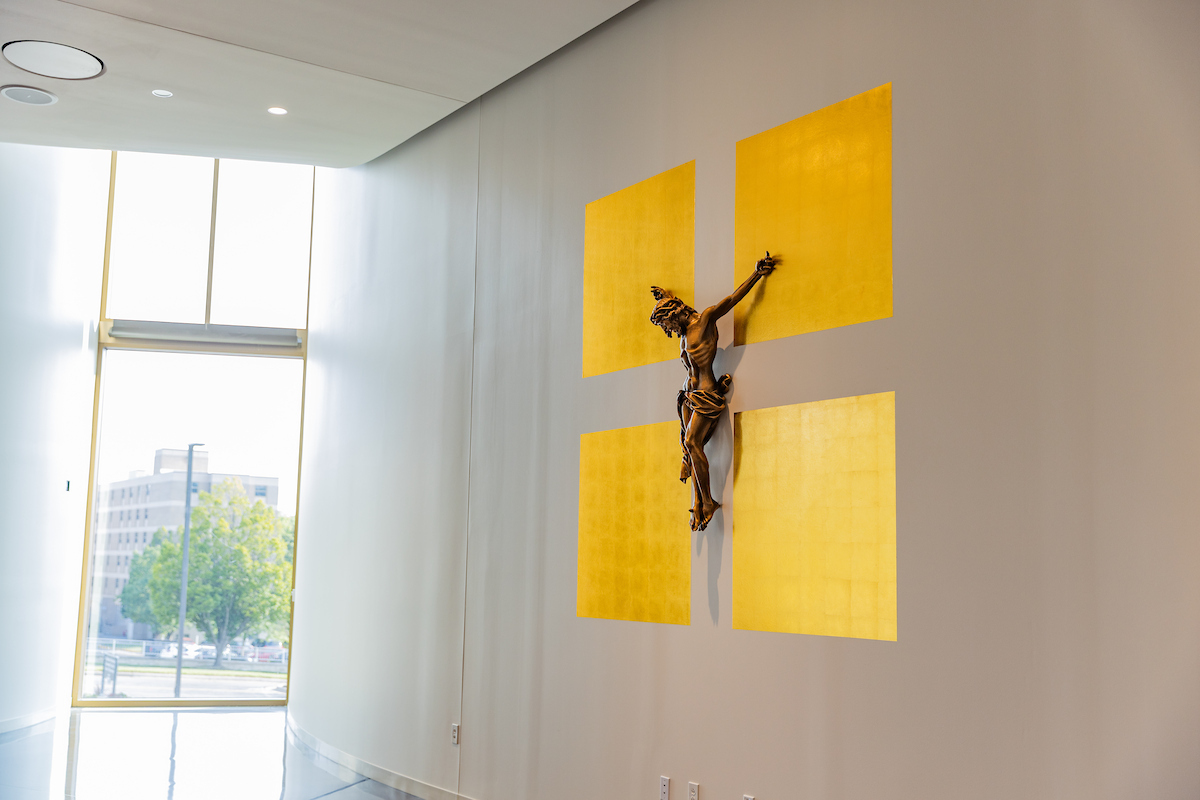 A crucifix hangs from a wall in Mabee Chapel, surrounded by yellow decorative squares