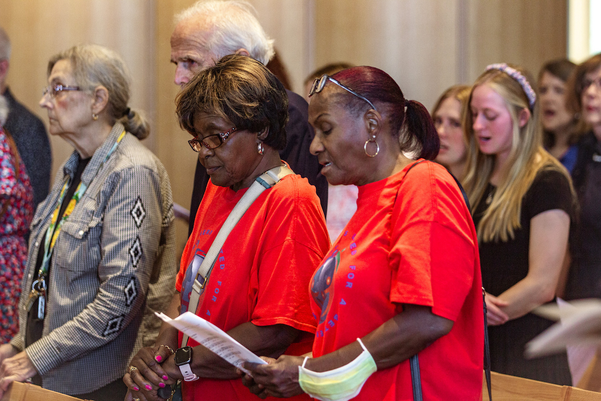 Women stand in a row of chairs during a Mass