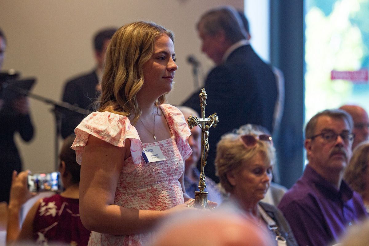 A female student walks with a cross in Mabee Chapel