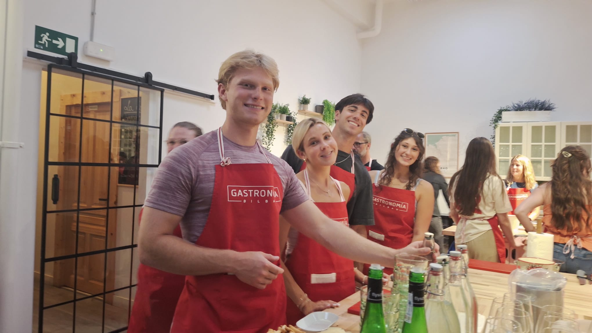 A group of students wearing red aprons smile for a picture during a cooking class at Gastronomía Bilbao in Bilbao, Spain