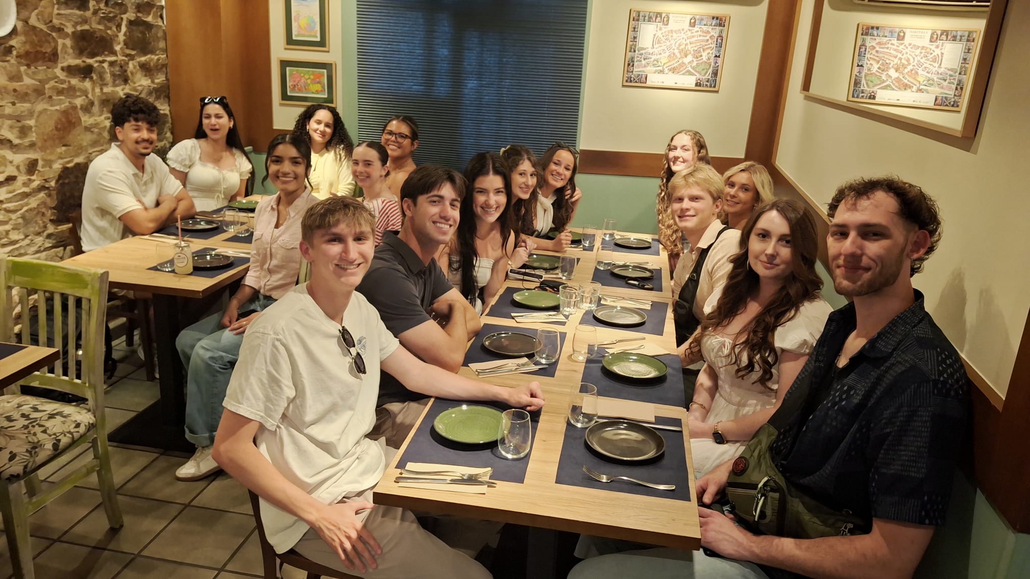 A group photo of study abroad participants at dinner in Santiago de Compostela, Spain and smiling at camera.