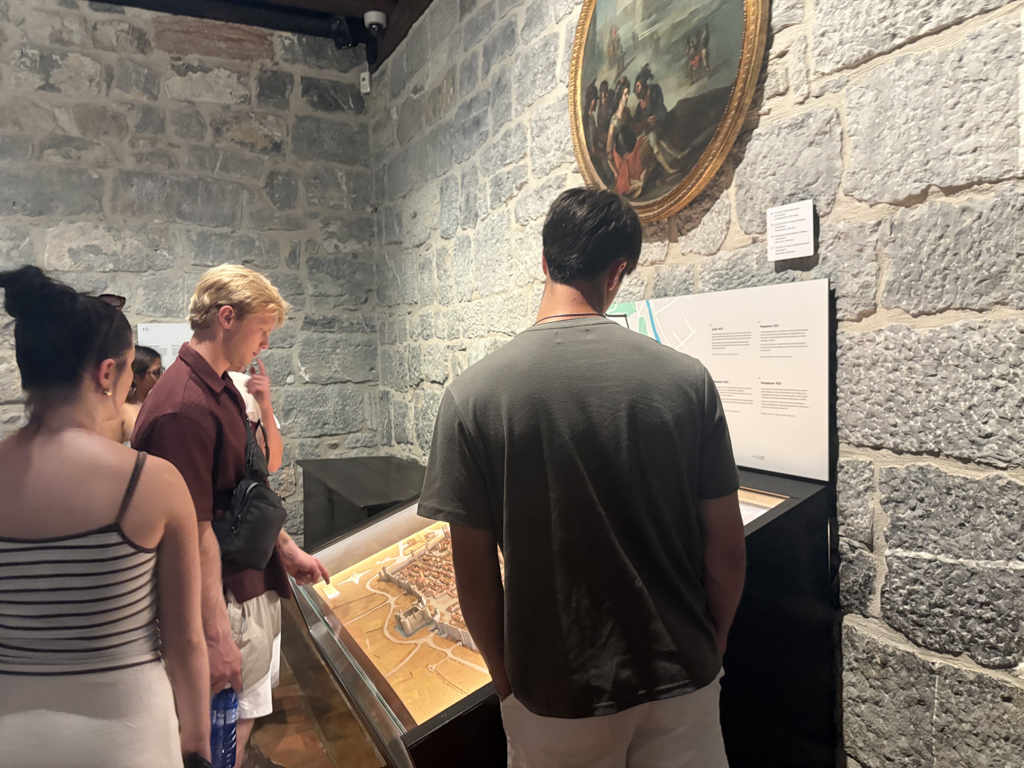 Three study abroad participants look down at exhibit in Loyola Spain