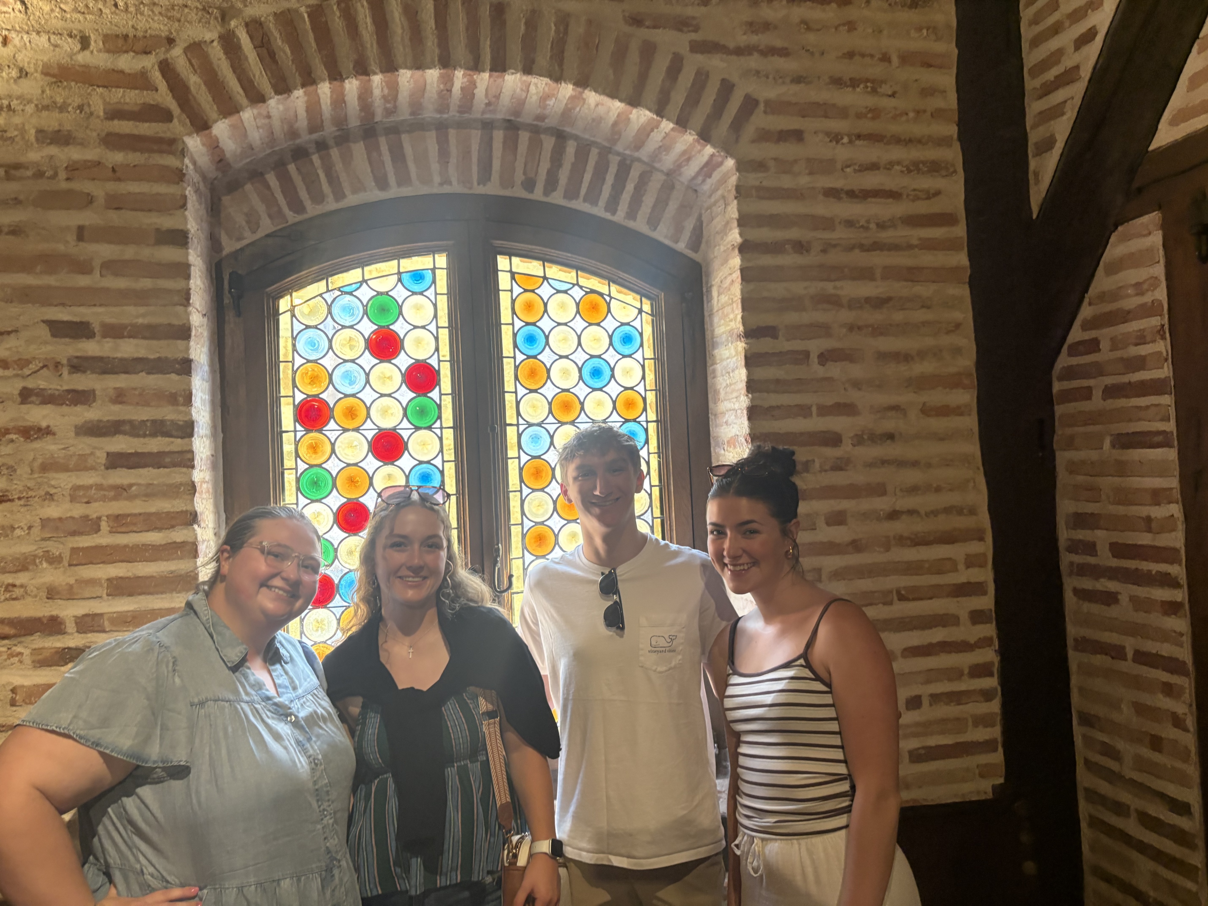 A group of four study abroad participants stand in front of a stained glass window at the birthplace and family home of St. Ignatius in Loyola, Spain