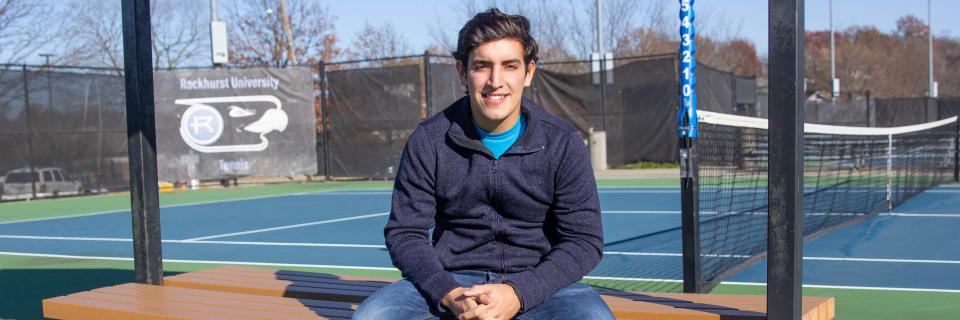 Nico Leon sits on a bench on the tennis courts.