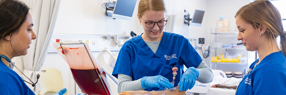 Nursing students practicing procedures on an arm