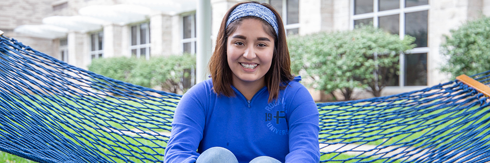 Paola Rodriguez sits on a hammock on campus.