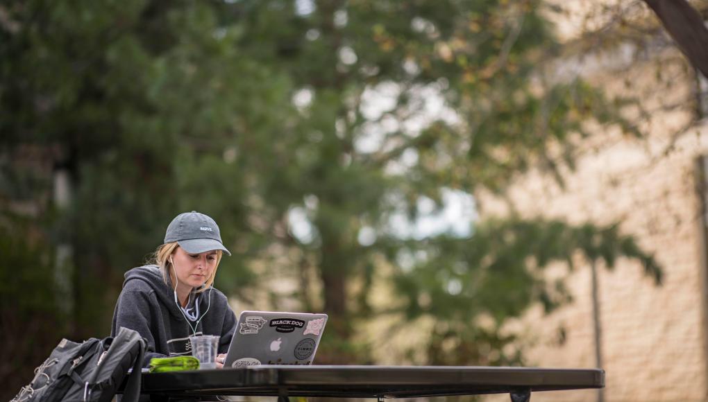 Student at table studying on laptop