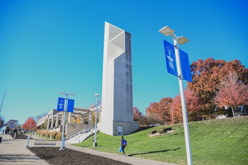 Rockhurst University Bell Tower on a sunny day with a student walking on the sidewalk