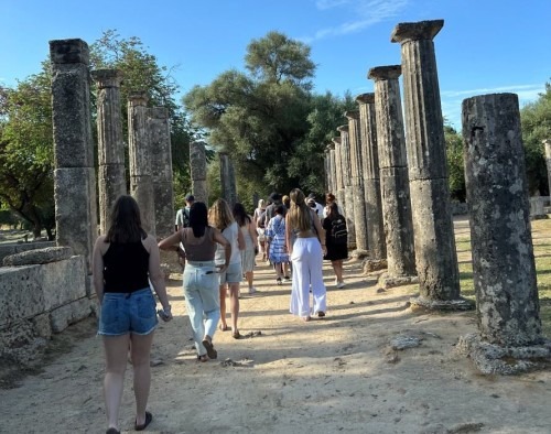 Study abroad students and leaders walk through Roman ruins/pillars in Spain