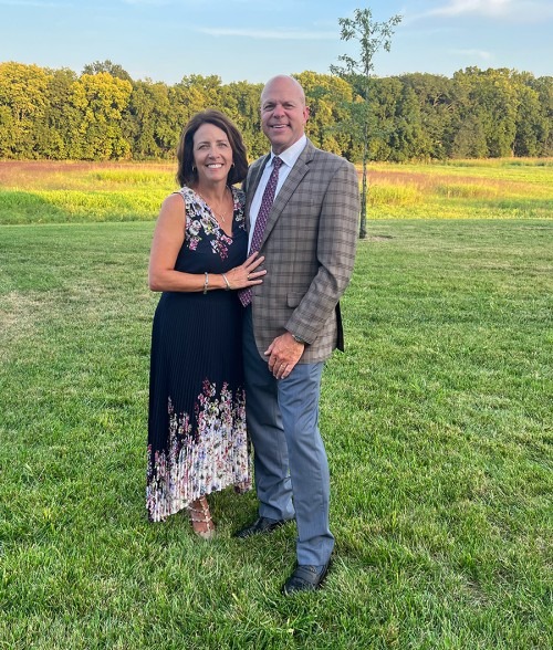 Laura (McGrady) and Bob Bira stand in the grass, forest behind them