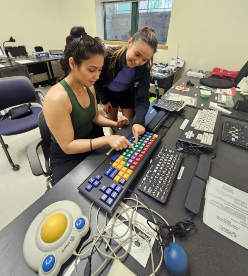 Two occupational therapists work with assistive technology keyboard and additional equipment