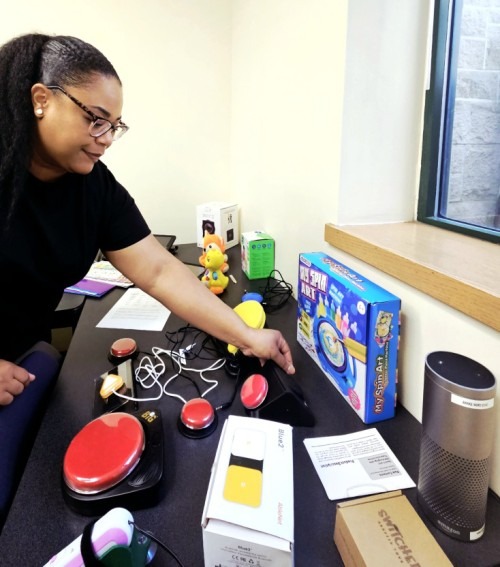 A worker adjusts assistive technology equipment on a table