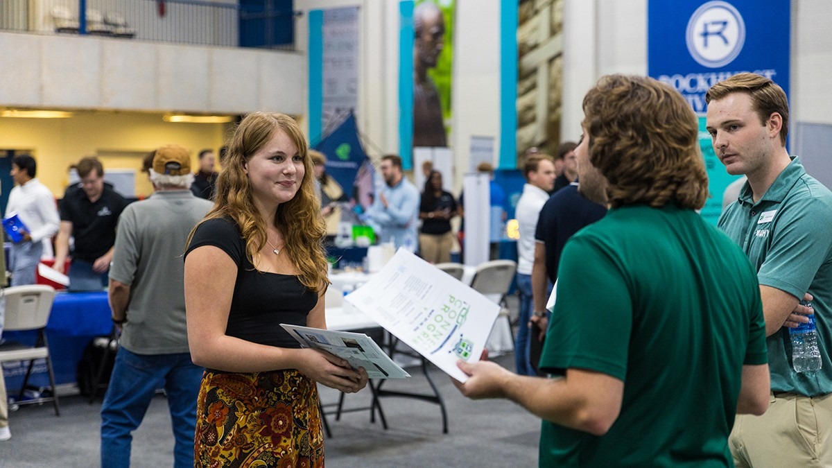 A company representative talks with a Rockhurst University student during a career fair