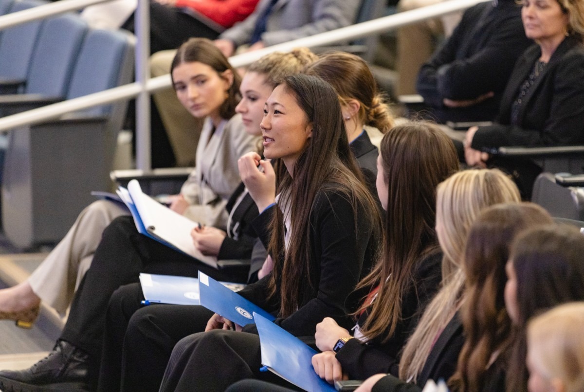 A women asks a question while sitting in a row of learners