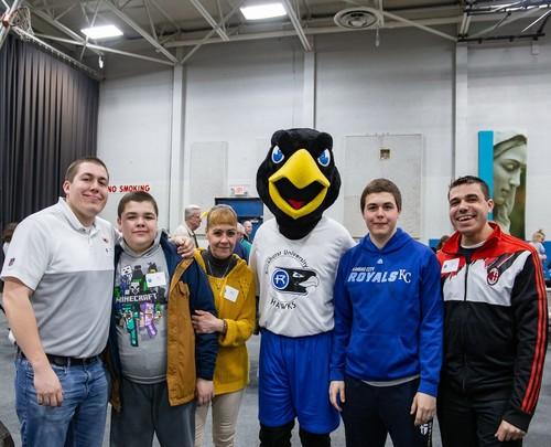 A group of event attendees standing with Rock E. Hawk