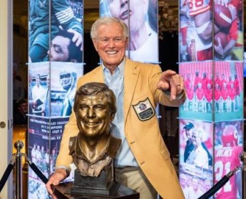 Dick Vermeil posing behind his Hall of Fame bust