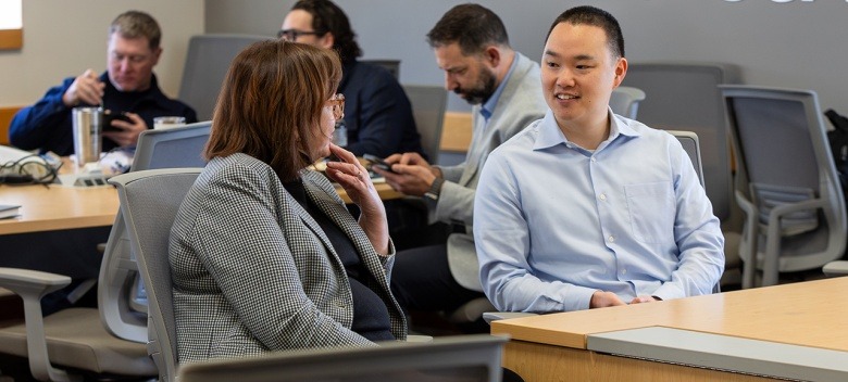 Students talk while sitting at tables in an MBA class at Rockhurst University