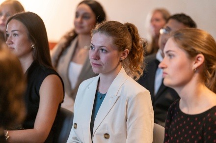 Students in business-casual listen intently 