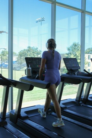 A female student walks on a treadmill in the Magis Activity Center (MAC) while she looks out over campus