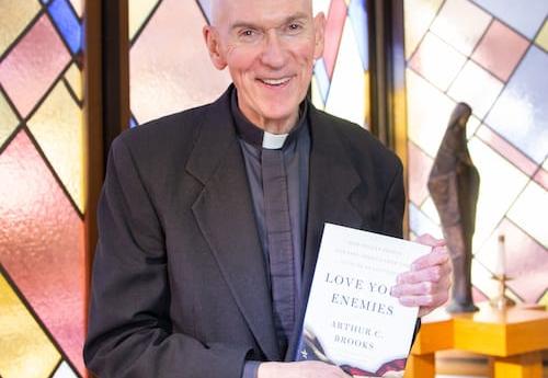 Fr. Curran holding a copy of a book