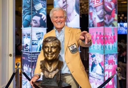 Dick Vermeil posing behind his Hall of Fame bust