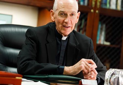 Fr. Curran sitting at his desk